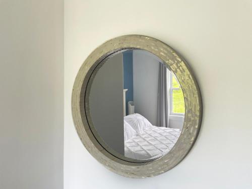 a round mirror hanging on a wall in a room at Gateway to Greenwich Suites in Saint Peters