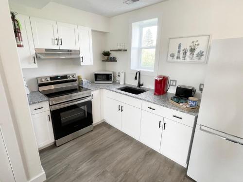 a kitchen with white cabinets and black appliances at Gateway to Greenwich Suites in Saint Peters