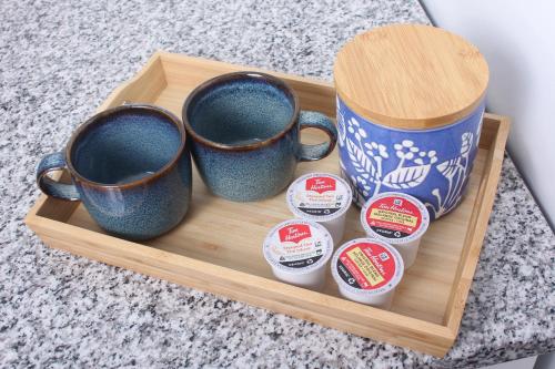 a tray with three coffee mugs and four cups at Gateway to Greenwich Suites in Saint Peters
