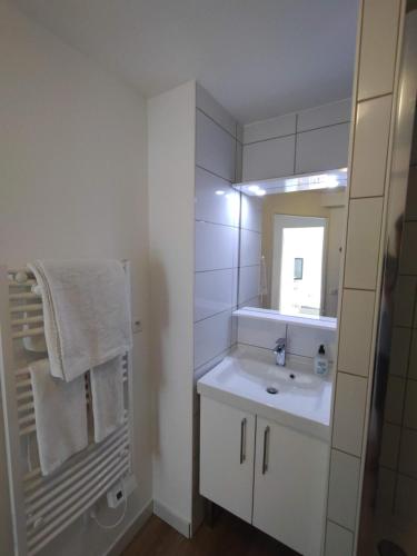ein weißes Badezimmer mit einem Waschbecken und einem Spiegel in der Unterkunft 10 mins walk to metro,La Défense, renovated in Courbevoie