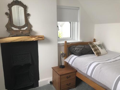 a bedroom with a bed and a mirror over a fireplace at Seacot Cottage in the heart of the Highlands in South Kessock