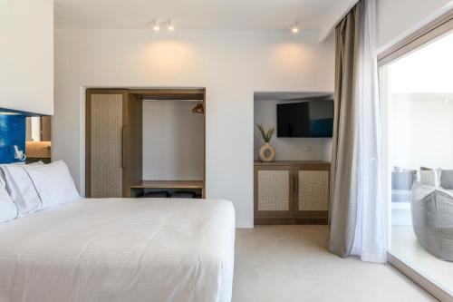 a bedroom with a white bed and a large window at Muro Suites in Ornos