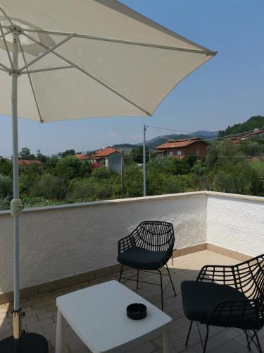 a patio with two chairs and a table and an umbrella at Villa Flora Affittacamere in Luni