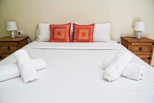 Una cama blanca con almohadas naranjas y blancas. en Sunset Apartment, Puerto Santiago, en Puerto de Santiago