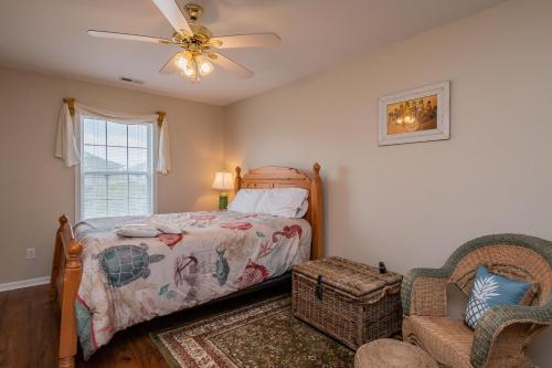 1 dormitorio con 1 cama, ventilador y silla en Seashell Cottage by Oak Island Accommodations, en Oak Island