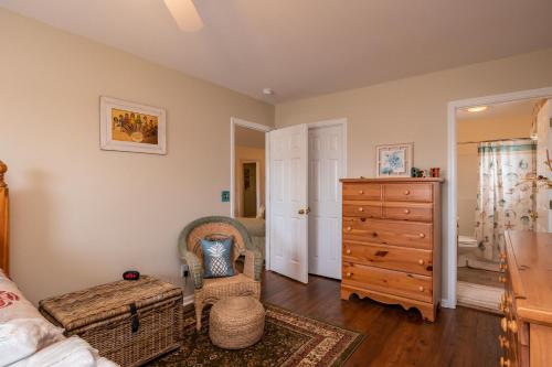 1 dormitorio con 1 cama, vestidor y silla en Seashell Cottage by Oak Island Accommodations, en Oak Island