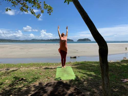 a woman standing on a green yoga mat on the beach at The Inner Light Yoga Lodge in Sámara