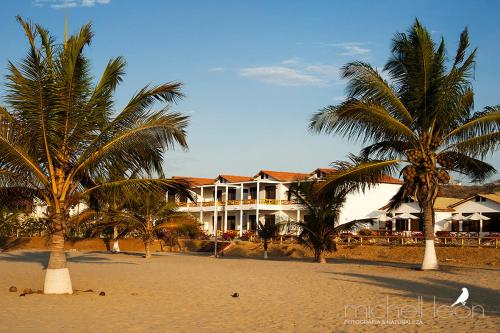 a building on the beach with palm trees and a bird at Amotape Comfort in Zorritos