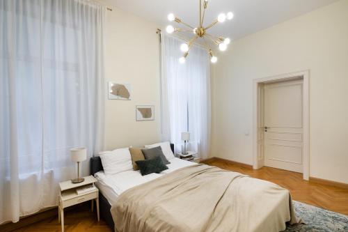 a white bedroom with a bed and a chandelier at Old Riga Modern and Spacious 2 bedroom Apartment in Rīga