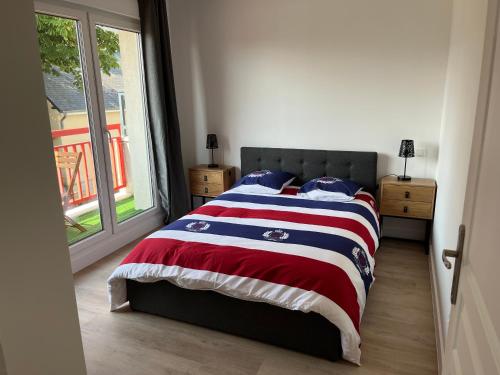 1 dormitorio con 1 cama con manta roja blanca y azul en Appartement tout confort, en Bréhal