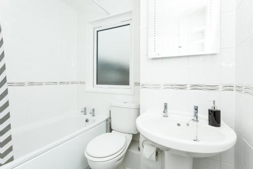 a white bathroom with a toilet and a sink at Gatwick Place - 4 bed 2 bath self contained house with private garden in Horley