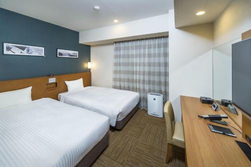 a hotel room with two beds and a desk at Sotetsu Fresa Inn Fujisawaeki Minamiguchi in Fujisawa