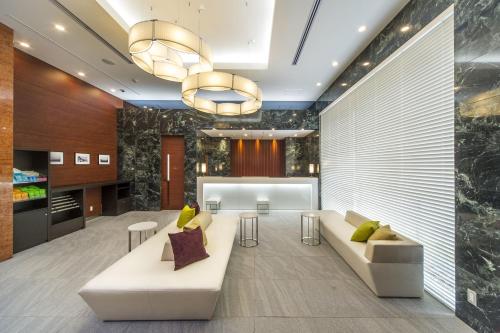 a lobby with a white couch and a table at Sotetsu Fresa Inn Fujisawaeki Minamiguchi in Fujisawa