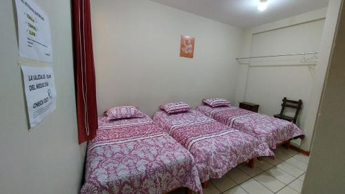 1 dormitorio con 2 camas y mantas rosas en JUMANA, en Nazca