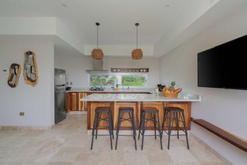a kitchen with a island with bar stools and a tv at Valhalla Residences by Biwa in Tulum