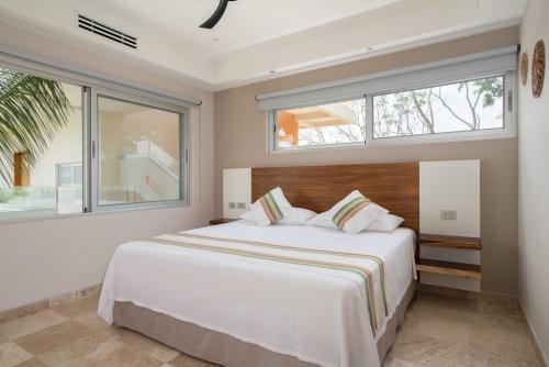 a bedroom with a large bed and two windows at Valhalla Residences by Biwa in Tulum