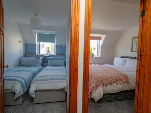ein Schlafzimmer mit zwei Betten und einem Spiegel in der Unterkunft The Little Cottage in Weymouth