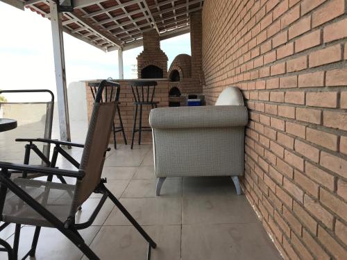a brick wall and chairs on a patio at Cobertura com piscina e churrasqueira - Guarujá in Guarujá