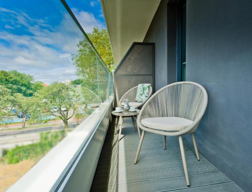 a white chair sitting on a balcony with a window at Unique Baltic Apartments - Apartament z garażem in Kołobrzeg