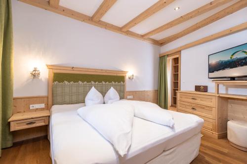 a bedroom with a white bed and a flat screen tv at Landhaus Dorfbäck in Stumm