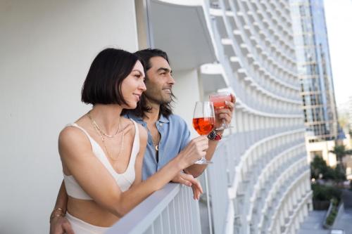 a man and woman standing on a balcony with a glass of wine at Fairmont Century Plaza Los Angeles at Beverly Hills in Los Angeles