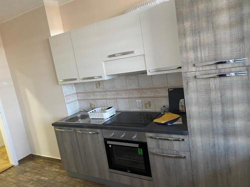 a kitchen with white cabinets and a sink at Apartman Čelarevo centar in Čelarevo