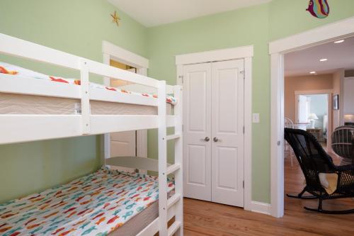 a bedroom with two bunk beds and a desk at Turtle Watch Too by Oak Island Accommodations in Caswell Beach