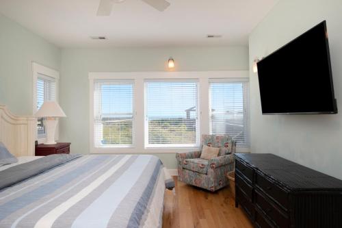 a bedroom with a bed and a flat screen tv at Turtle Watch Too by Oak Island Accommodations in Caswell Beach
