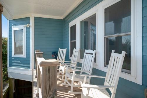 a group of white chairs sitting on a porch at Turtle Watch Too by Oak Island Accommodations in Caswell Beach