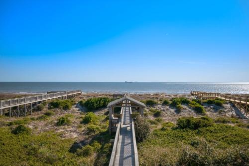 a boardwalk over the beach with the ocean in the background at Turtle Watch Too by Oak Island Accommodations in Caswell Beach