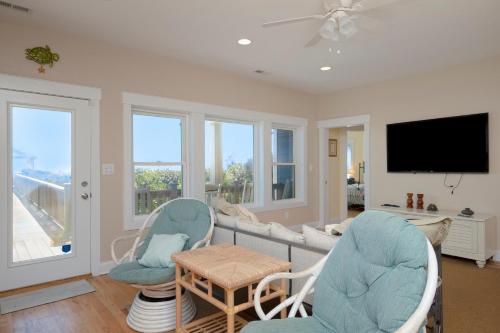 a living room with a couch and chairs and a tv at Turtle Watch Too by Oak Island Accommodations in Caswell Beach