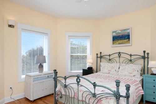 a bedroom with a bed and two windows at Turtle Watch Too by Oak Island Accommodations in Caswell Beach