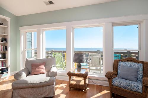 a living room with a couch and two chairs and windows at Turtle Watch Too by Oak Island Accommodations in Caswell Beach