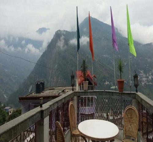 a table and chairs on a balcony with flags at Devbhoomi by StayApart in Ukhimath