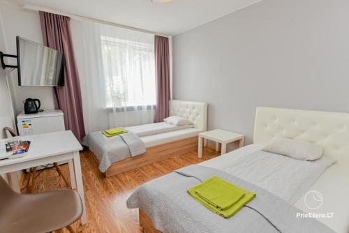 1 dormitorio con cama y ventana con sofá en Guest House Simona en Lazdijai