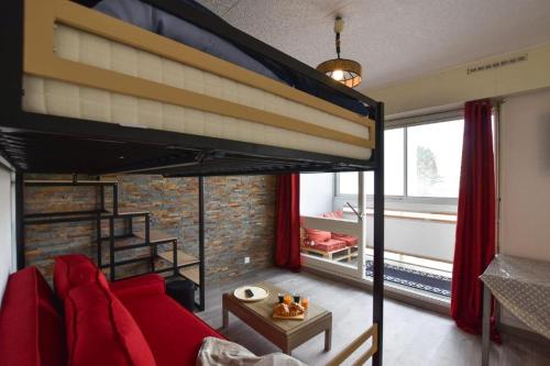 a bedroom with a loft bed with a red couch at Le P'tit bec ✹ Plage ✹ in Saint-Hilaire-de-Riez