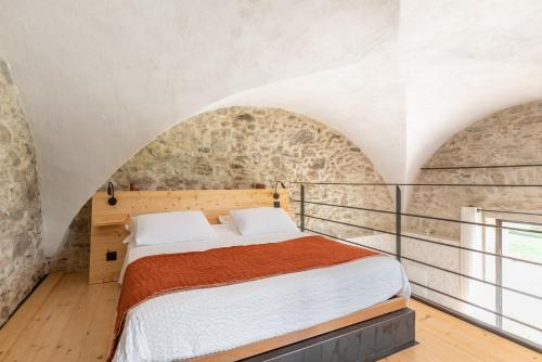 ラ・モット・セルヴォレックスにあるLes Tours Carréesの石壁のベッドルーム1室(ベッド1台付)