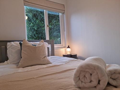 Park View Garden apartment في Salfords: غرفة نوم بسرير وملاءات بيضاء ونافذة