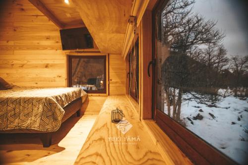 a log cabin with a bed and a window at Yuki Yama in Malalcahuello