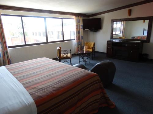 Cette chambre comprend un lit, un bureau et une fenêtre. dans l'établissement Hotel Lerma, à Lerma de Villada
