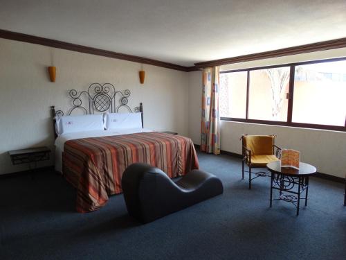 Hotel Lerma في Lerma de Villada: غرفه فندقيه بسرير وكرسي