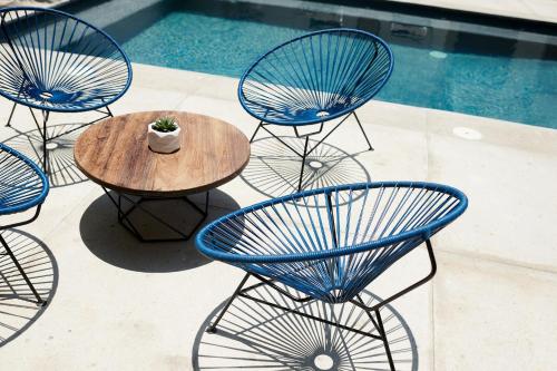 a group of blue chairs and a table next to a pool at Punta Mita Surf Lodge in Punta Mita