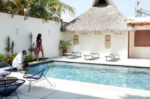 a woman walking next to a swimming pool with chairs at Punta Mita Surf Lodge in Punta Mita