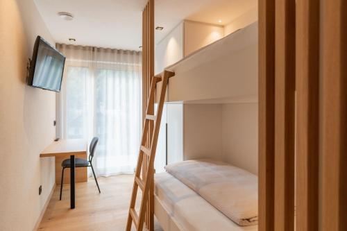 a small bedroom with a bunk bed and a desk at VANEA - Alp Relax Guesthouse in Chienes