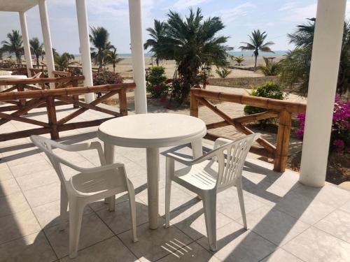 a white table and chairs on a patio with the beach at Amotape Comfort in Zorritos