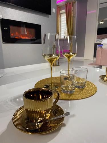 a table with two glasses of wine and plates on it at Apartament "Prezydencki" Centrum z dużą wanną dla Dwojga in Gniezno