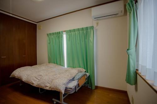 a bedroom with a bed and a window with green curtains at Guest house Lido Porte - Vacation STAY 95556v in Toba