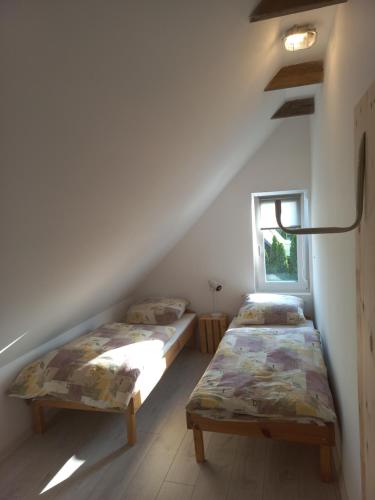 two beds in a attic room with a window at Zagroda Nadmorska Brzezina in Jastrzębia Góra