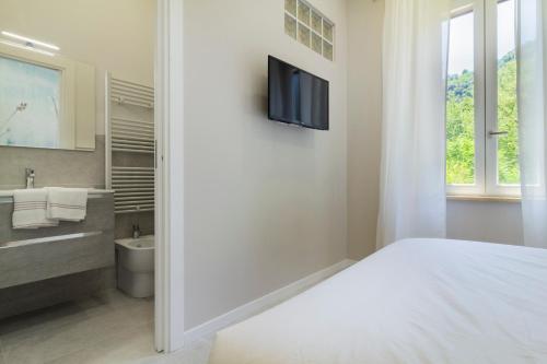 a white bathroom with a bed and a tv on a wall at Aria Marmore in Le Marmore
