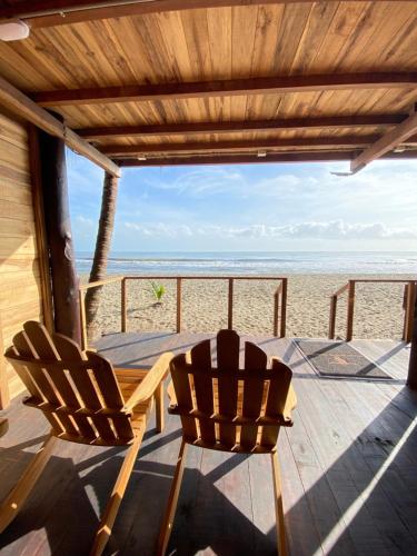two chairs and a table on a porch overlooking the beach at Palm Beach Hostal in Santa Marta
